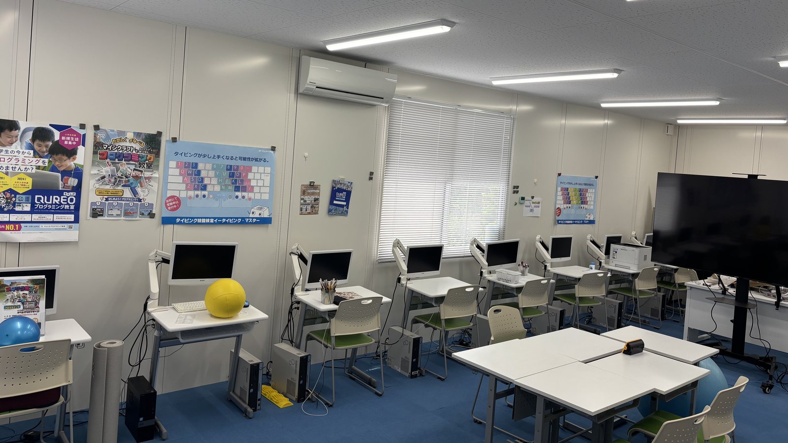 白い壁に沿って並ぶ一人用の学習席と、教室の中央に置かれた大きな机